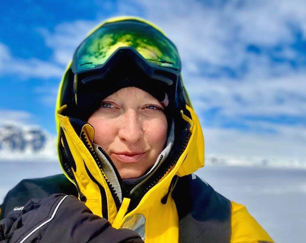 Ekaterina Uryupova in a black and yellow snow jacket with snow boarding goggles on her head.